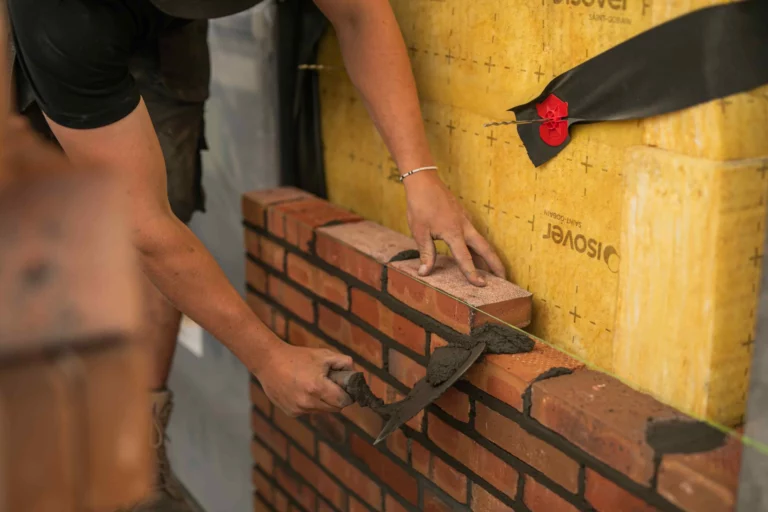 Een metselaar die een nieuwbouw huis metselt.