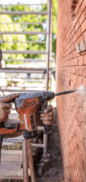 Gevelrenovatie door Kok Groep: een medewerker verwijdert voegen uit de gevel met een klophamer.